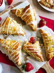 Strawberry turnovers arranged on parchment paper with fresh strawberries.