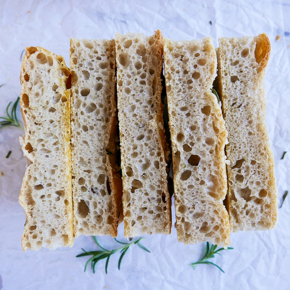 Five slices of focaccia lined up on parchment paper.