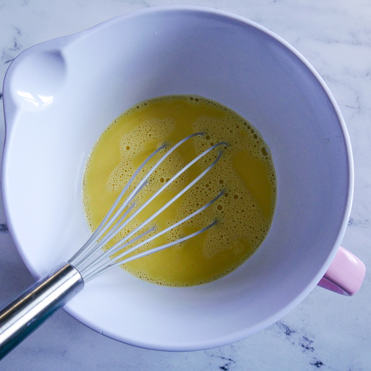 Whisked eggs and milk in a large bowl.