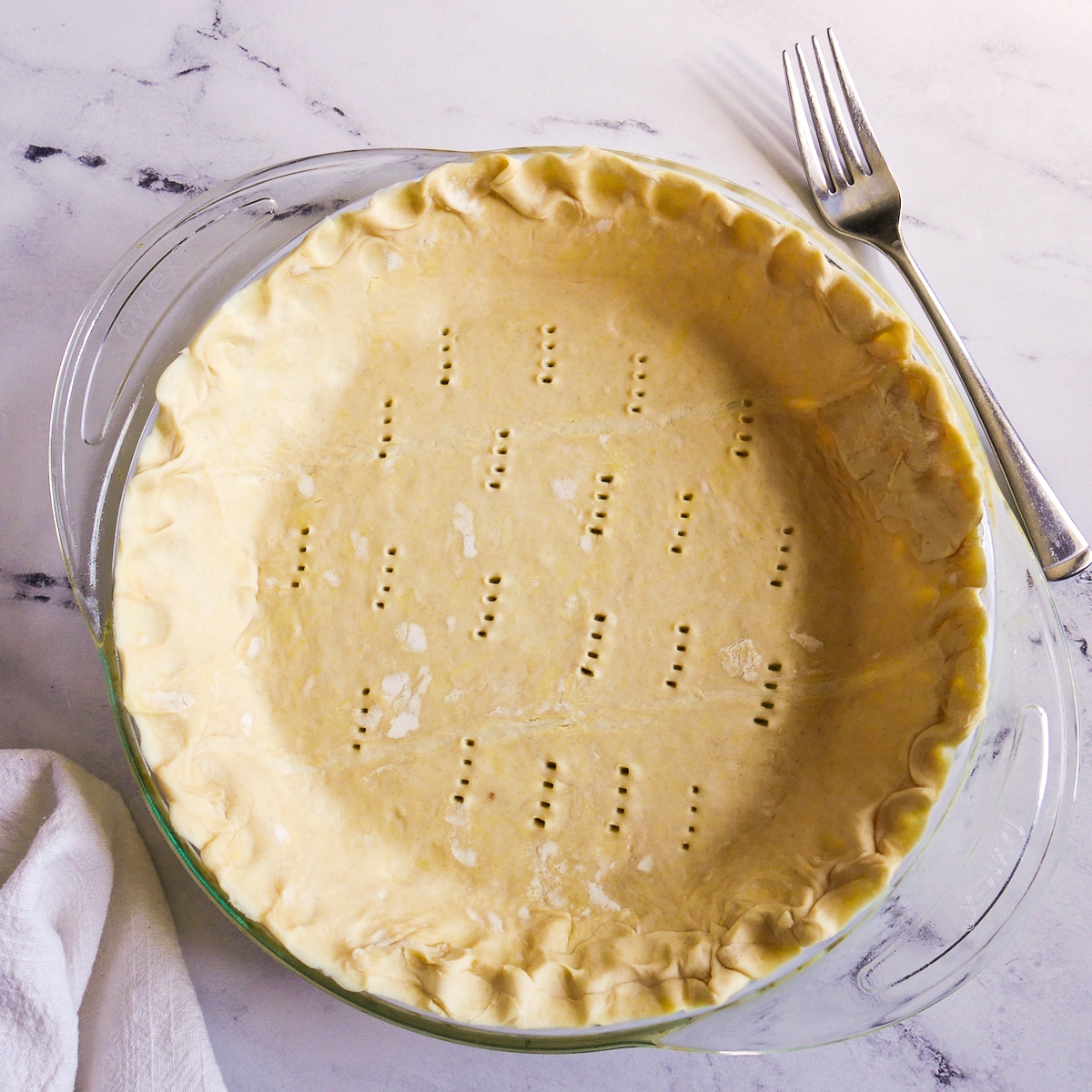 Puff pastry placed into a pie pan and pierced with a fork.