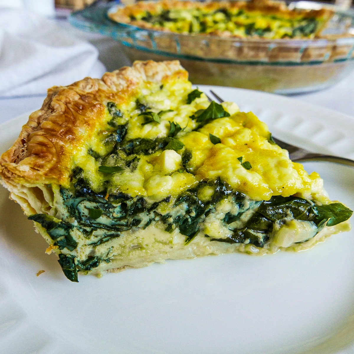 Slice of vegetable quiche arranged on a white plate.