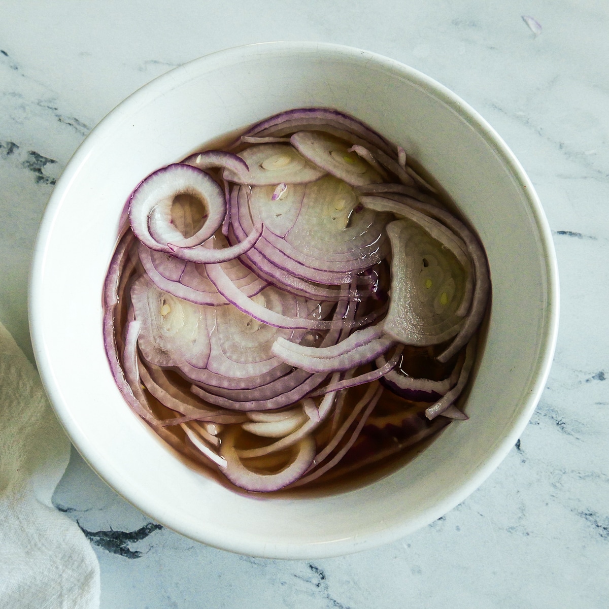 Sliced red onion resting in pickling liquid.