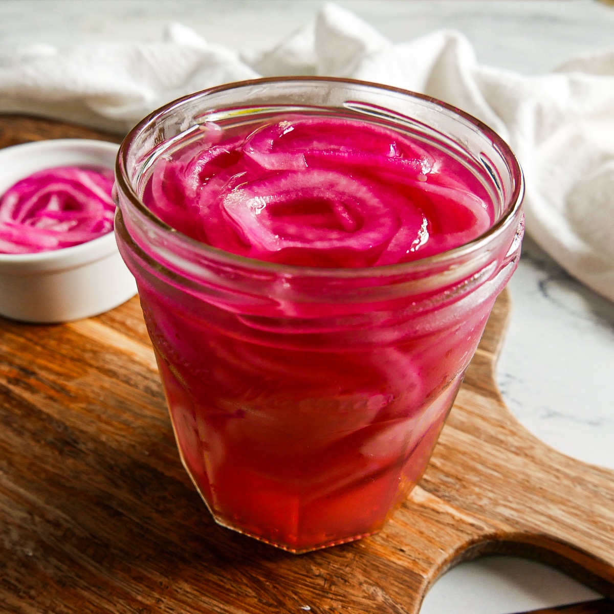 quick-pickled-onions.jpg Jar of quick pickled onions resting on a cutting board.