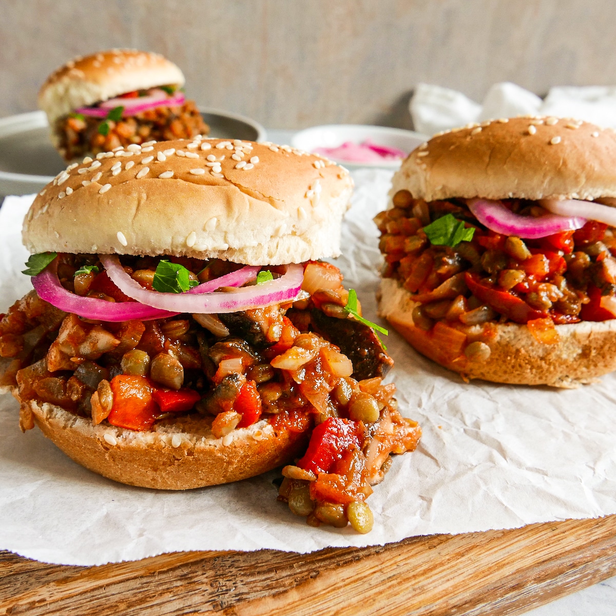 Three sloppy joes resting on parchment paper.
