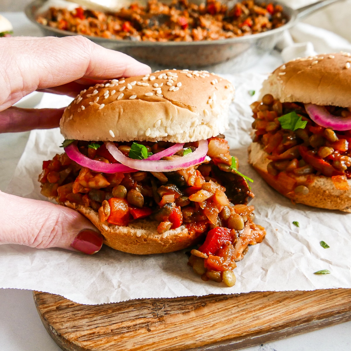 Hand picking up a lentil and mushroom sloppy joe sandwich.