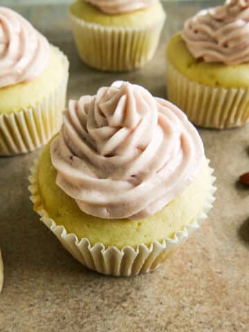 almond cupcakes arranged on a table with toasted almonds.