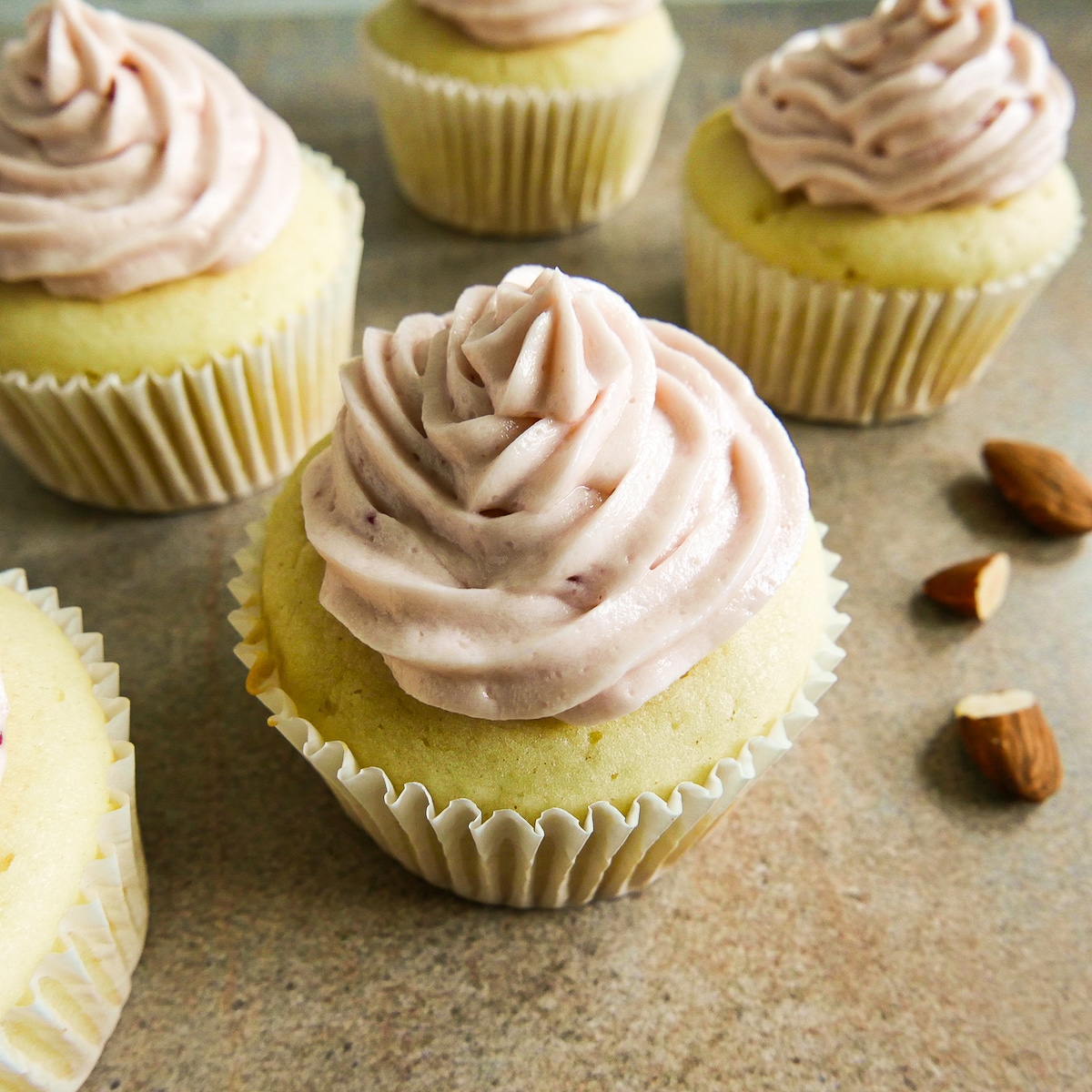 almond-cupcakes.jpg almond cupcakes arranged on a table with toasted almonds.