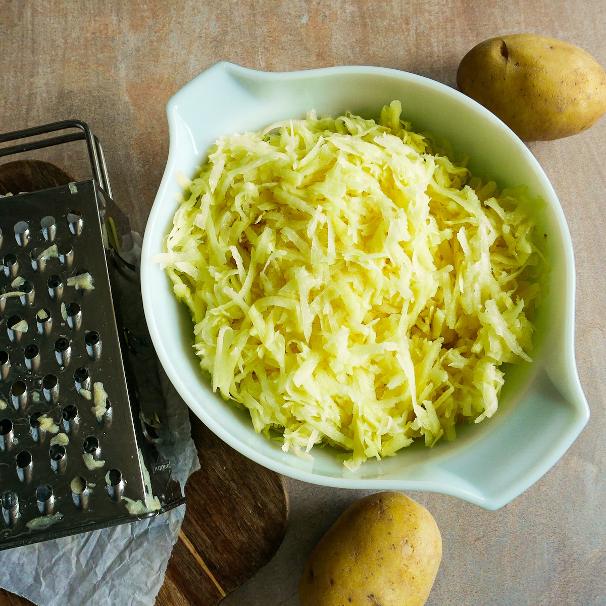 Grated potatoes and onion in a large mixing bowl.