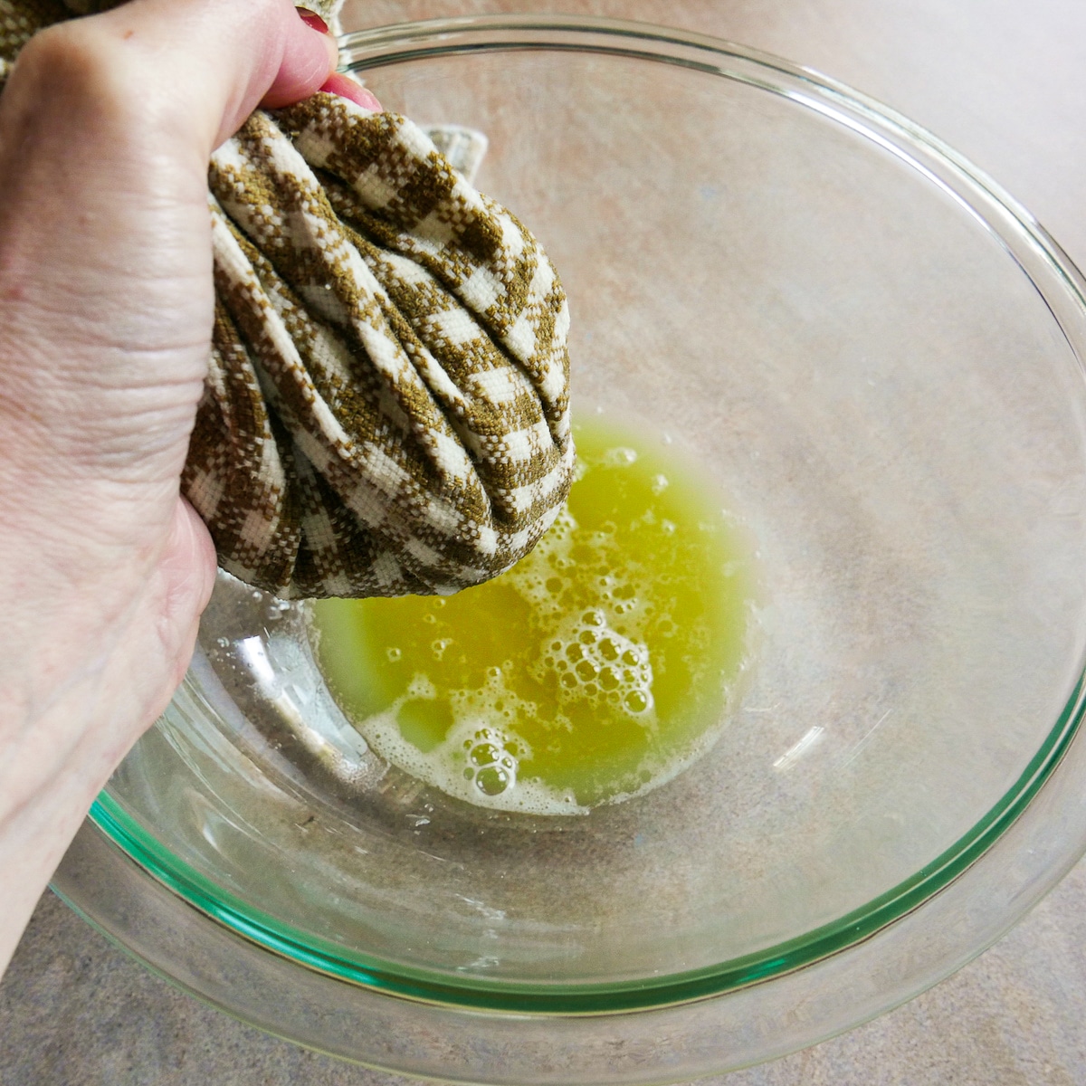 Squeezing out excess water into a bowl using a tea towel.