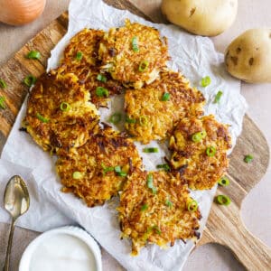 Crispy potato fritters arranged on a platter with dipping sauce.