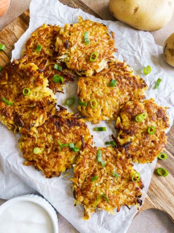 Crispy potato fritters arranged on a platter with dipping sauce.