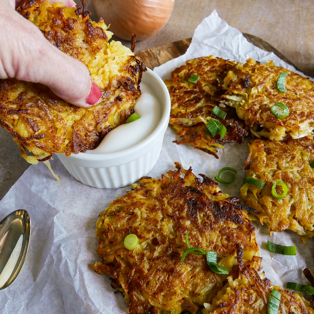 Shredded potato cakes arranged on a platter with one being dipped in sauce.