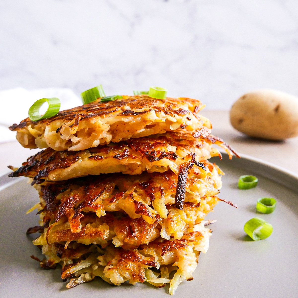 Stack of fritters on a gray plate with sliced green onions.