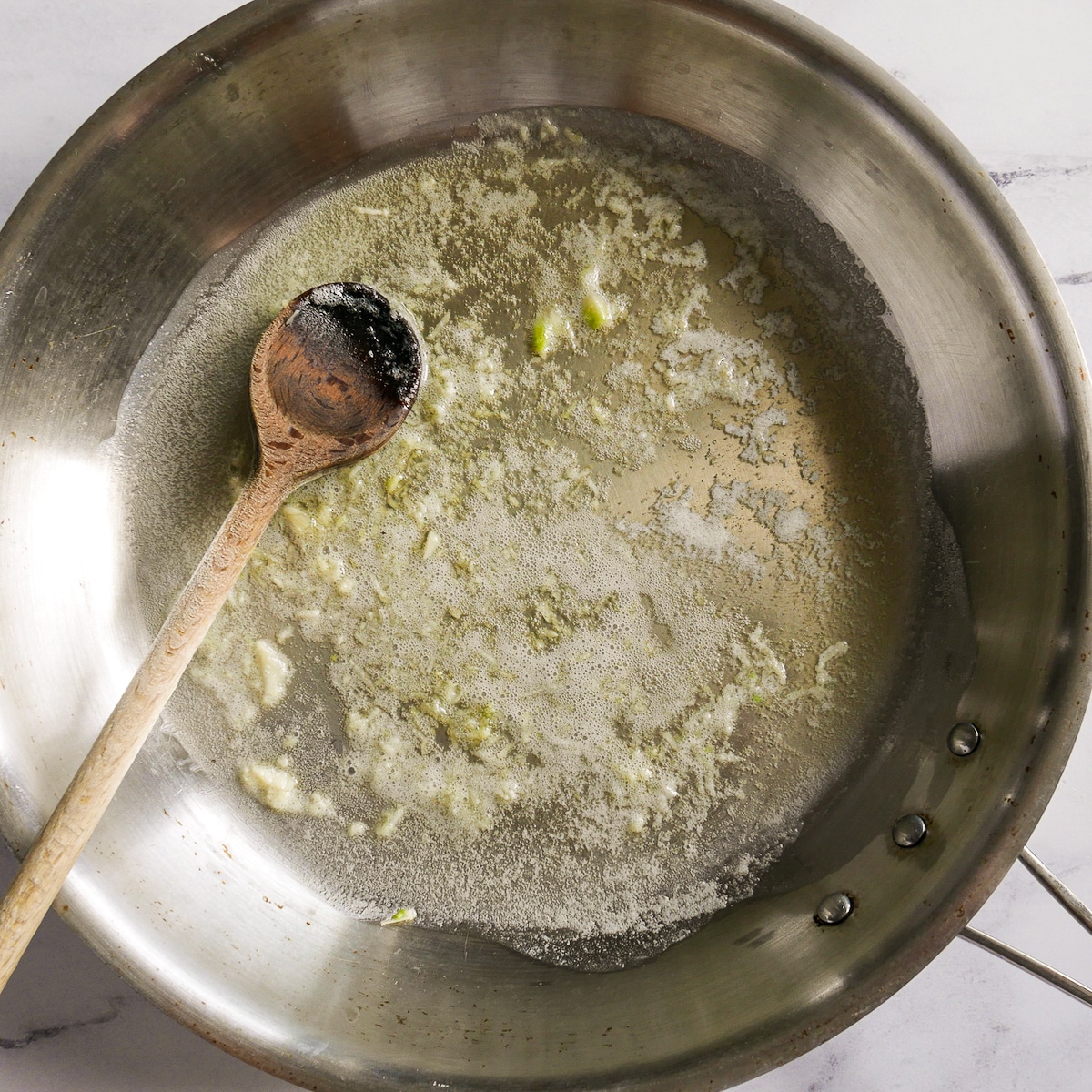 Minced garlic cooking in a large skillet of melted butter.