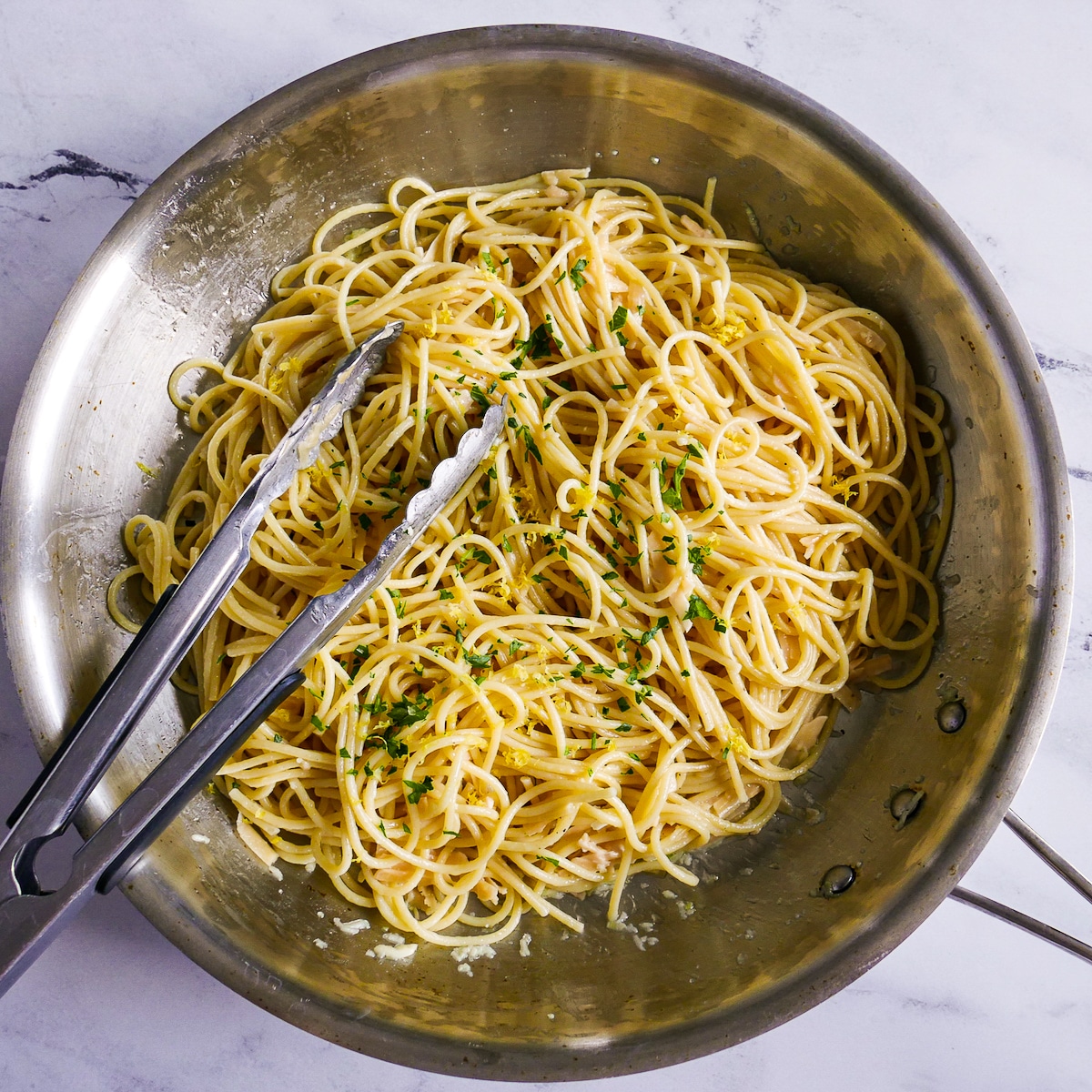 Noodles tossed with garlic butter, Parmesan, and lemon in a skillet.