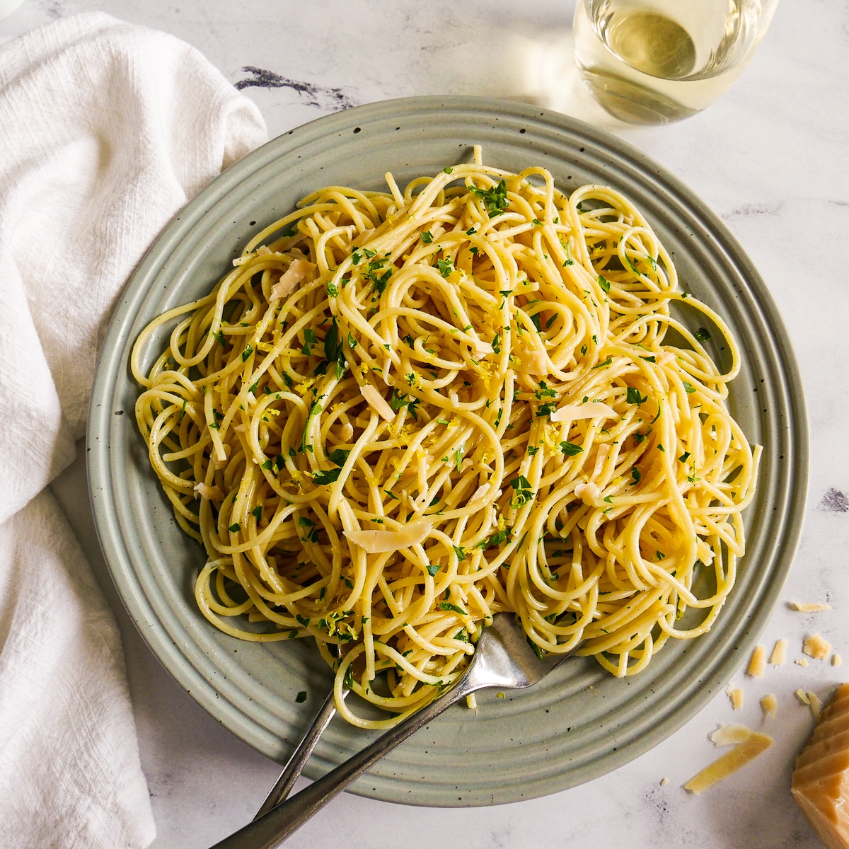 Plate of garlic buttered noodles with a glass of white wine.