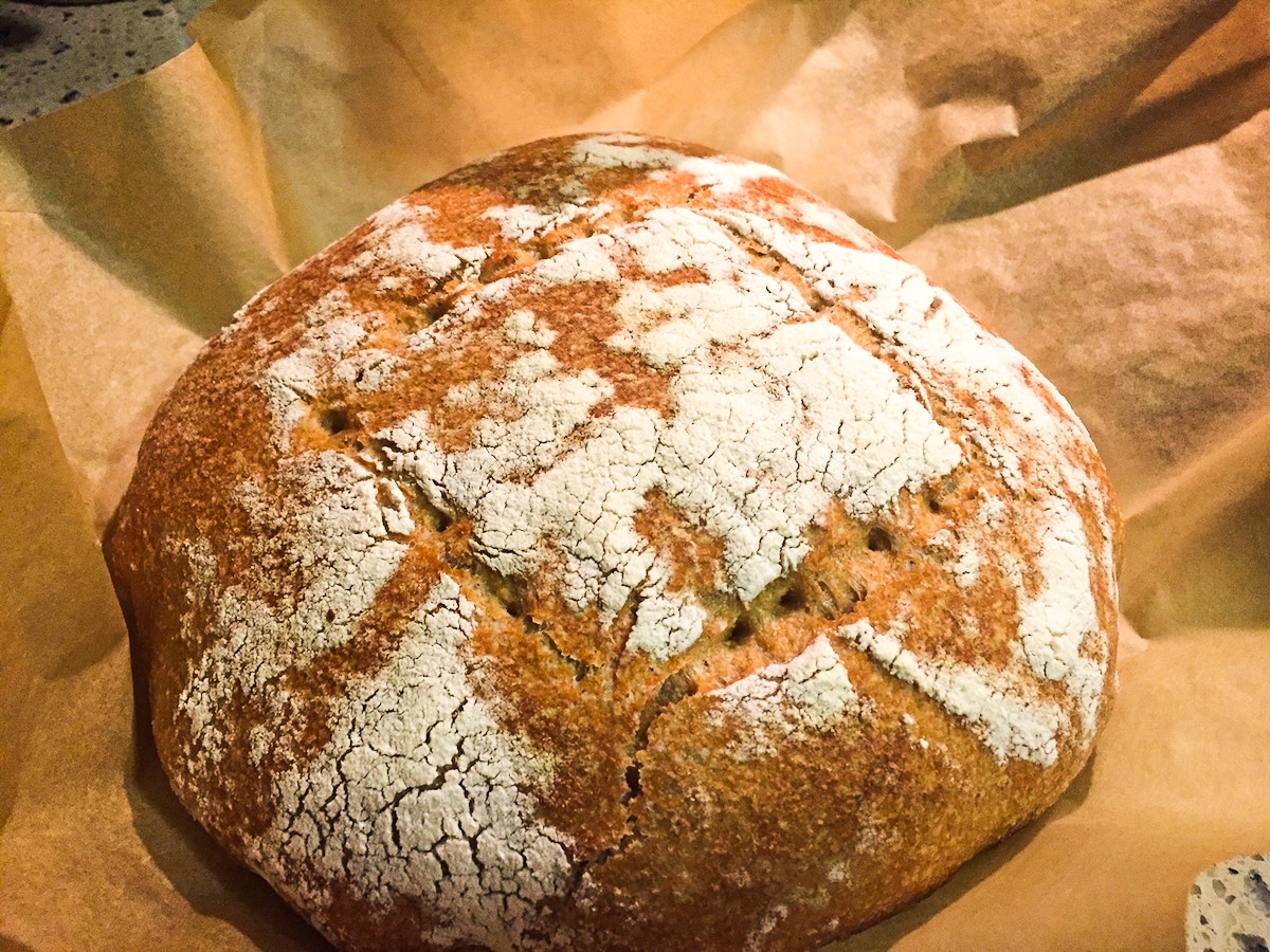 Loaf of sourdough resting on parchment paper. 