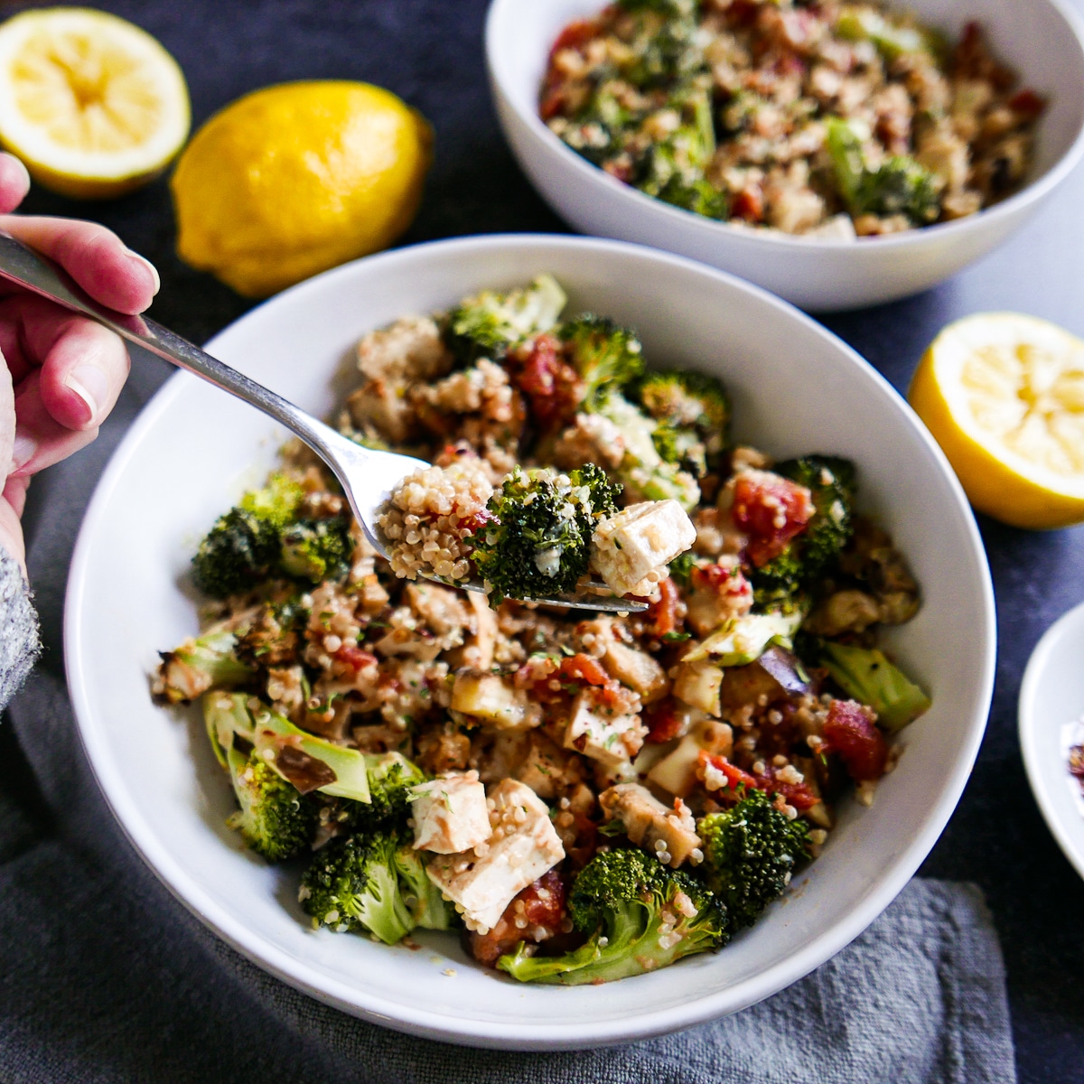 fork-lifting-bite-of-food.jpg Fork lifting up bite of assembled grain bowl with sliced lemons in the background.