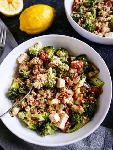 Fork resting in a quinoa bowl with roasted vegetables and tofu.