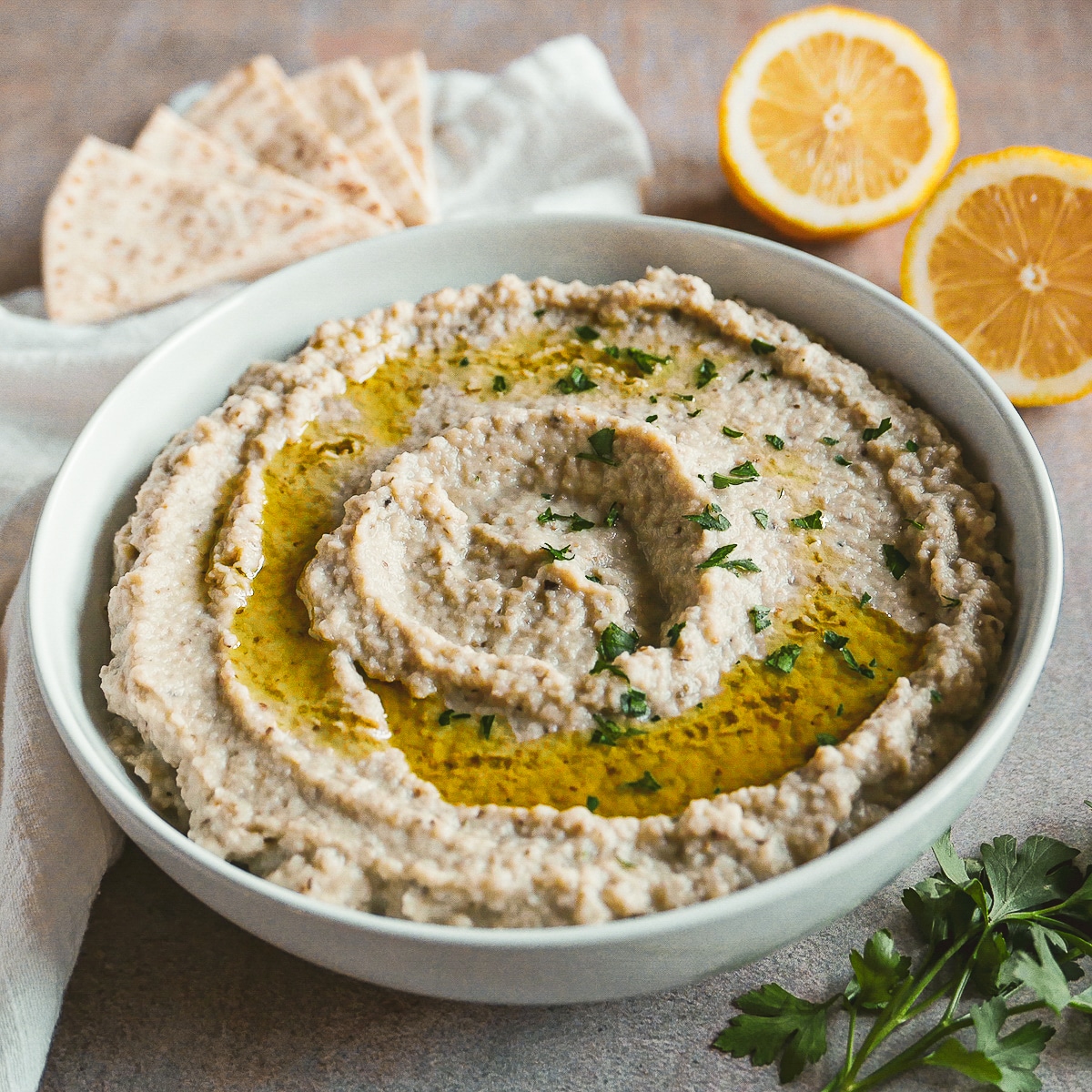 bowl of mutabal with pita and lemon in background.