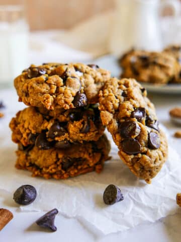 Stack of vegan pumpkin cookies arranged on parchment paper.