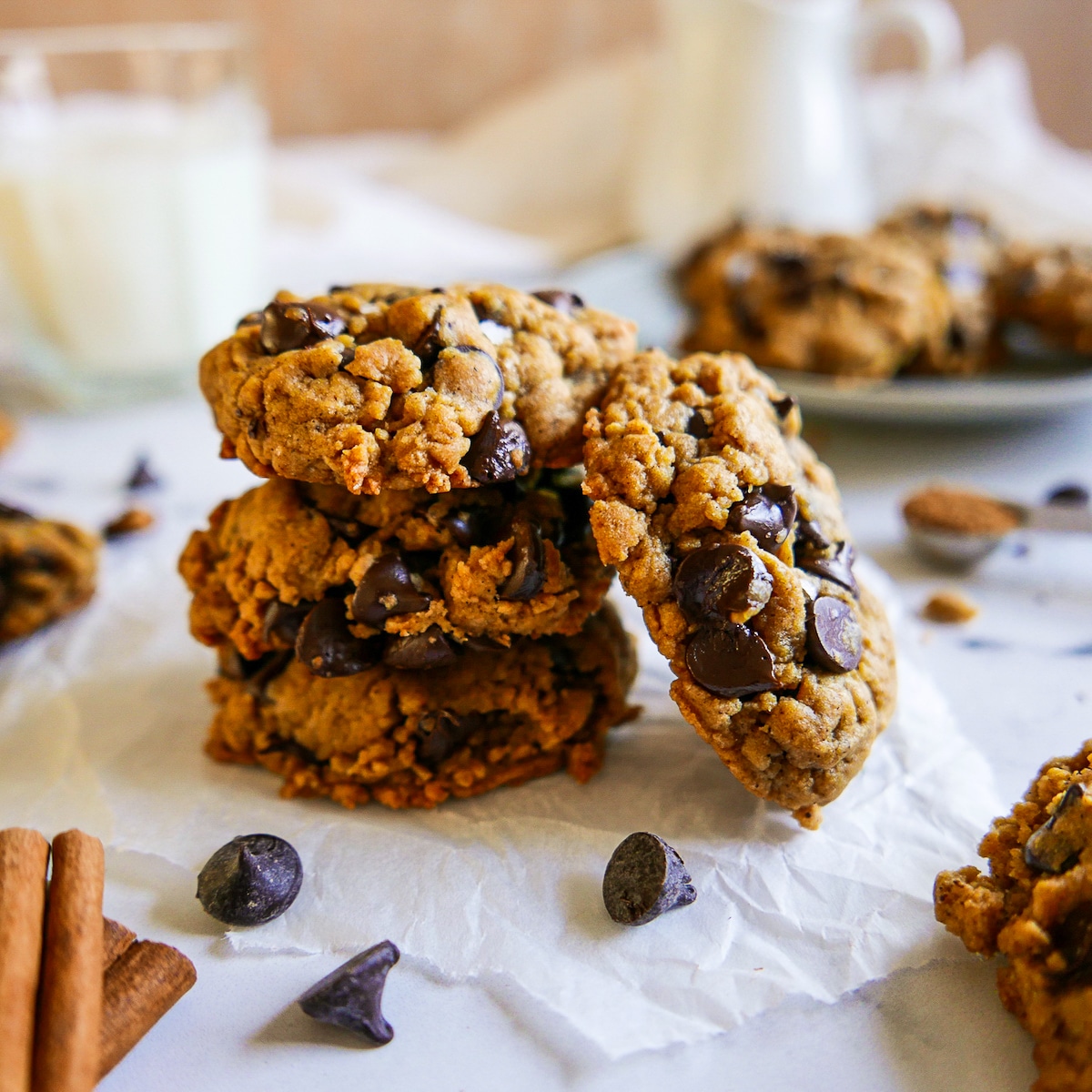 Stack of vegan pumpkin cookies arranged on parchment paper.