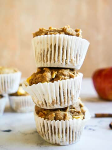 stack of apple muffins with an apple in the background.