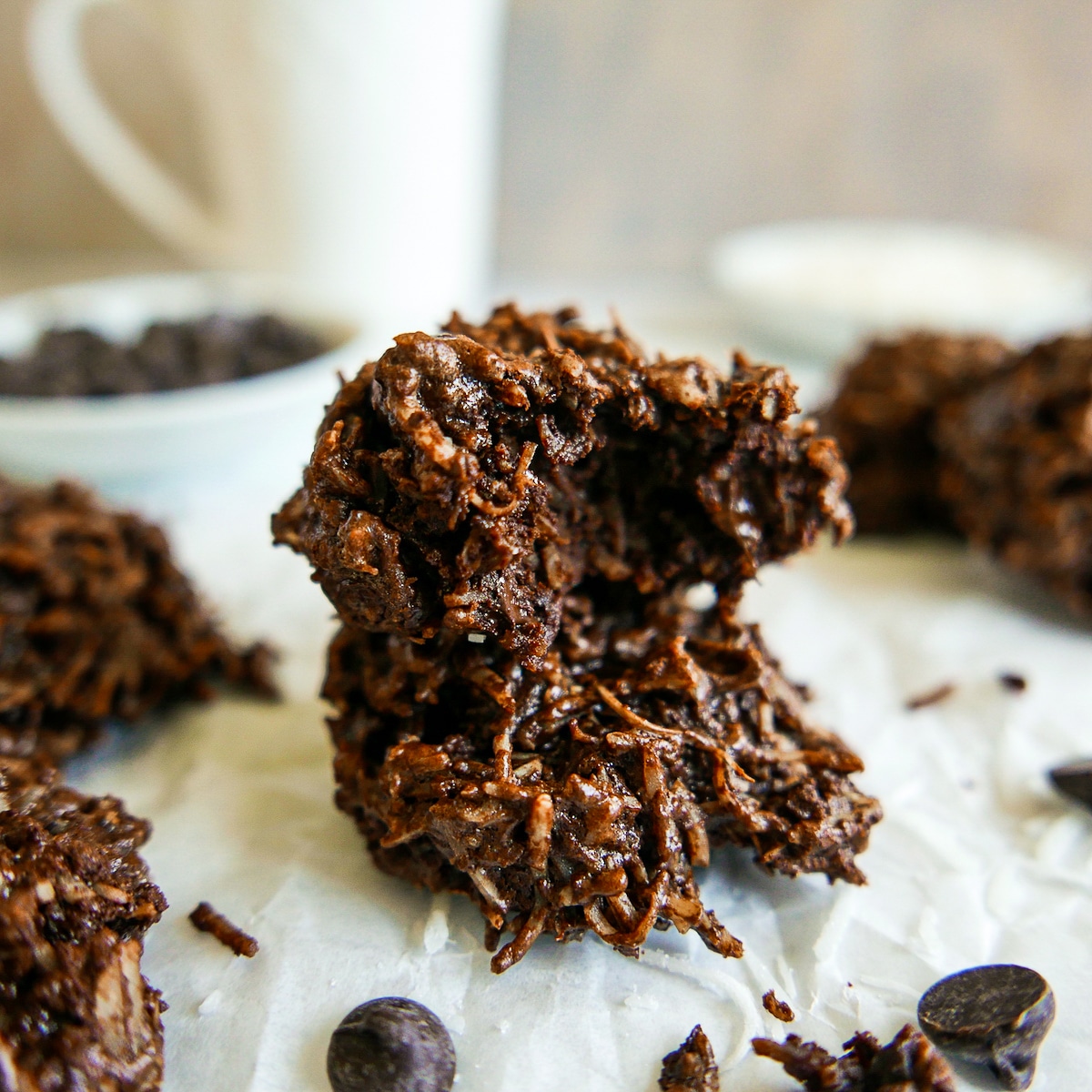 chocolate macaroons arranged on parchment paper with chocolate chips scattered around.