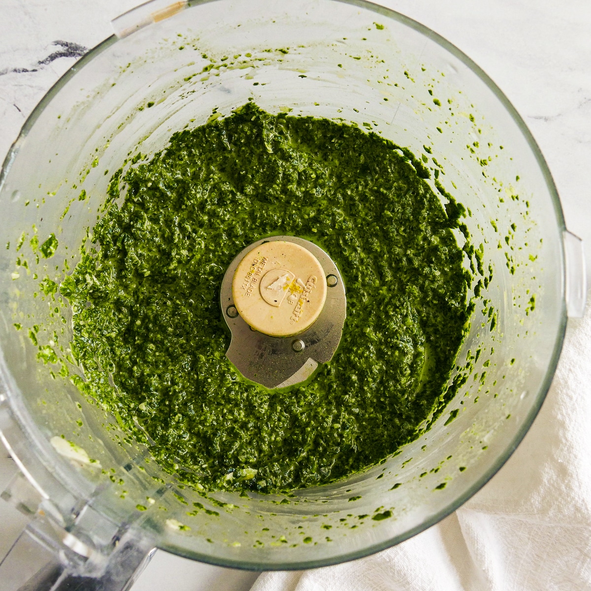 Green pasta sauce ingredients blended in a food processor.