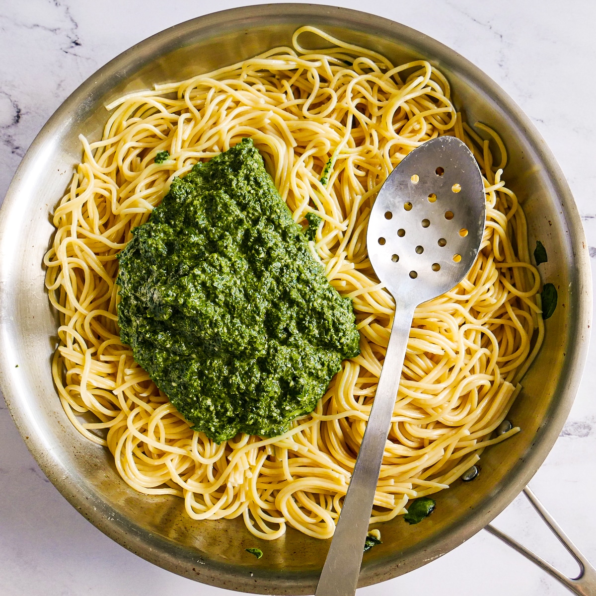 Green spinach sauce placed on top of cooked noodles.