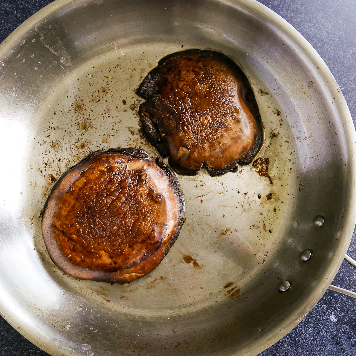 Cooked mushrooms flipped over in skillet.