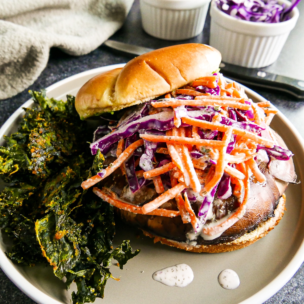 Assembled sandwich on a gray plate with kale chips.