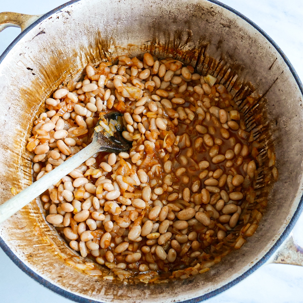 Great Northern beans added to pot of seasoned onions.