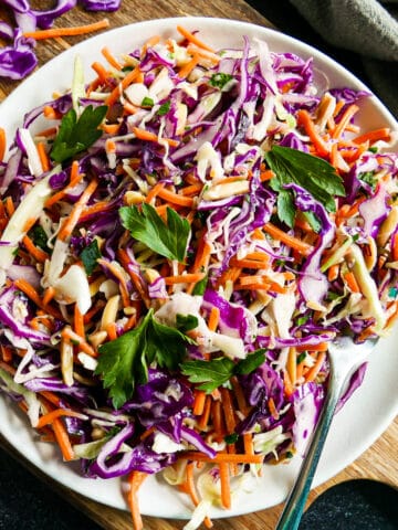 plate of purple cabbage coleslaw garnished with fresh parsley.