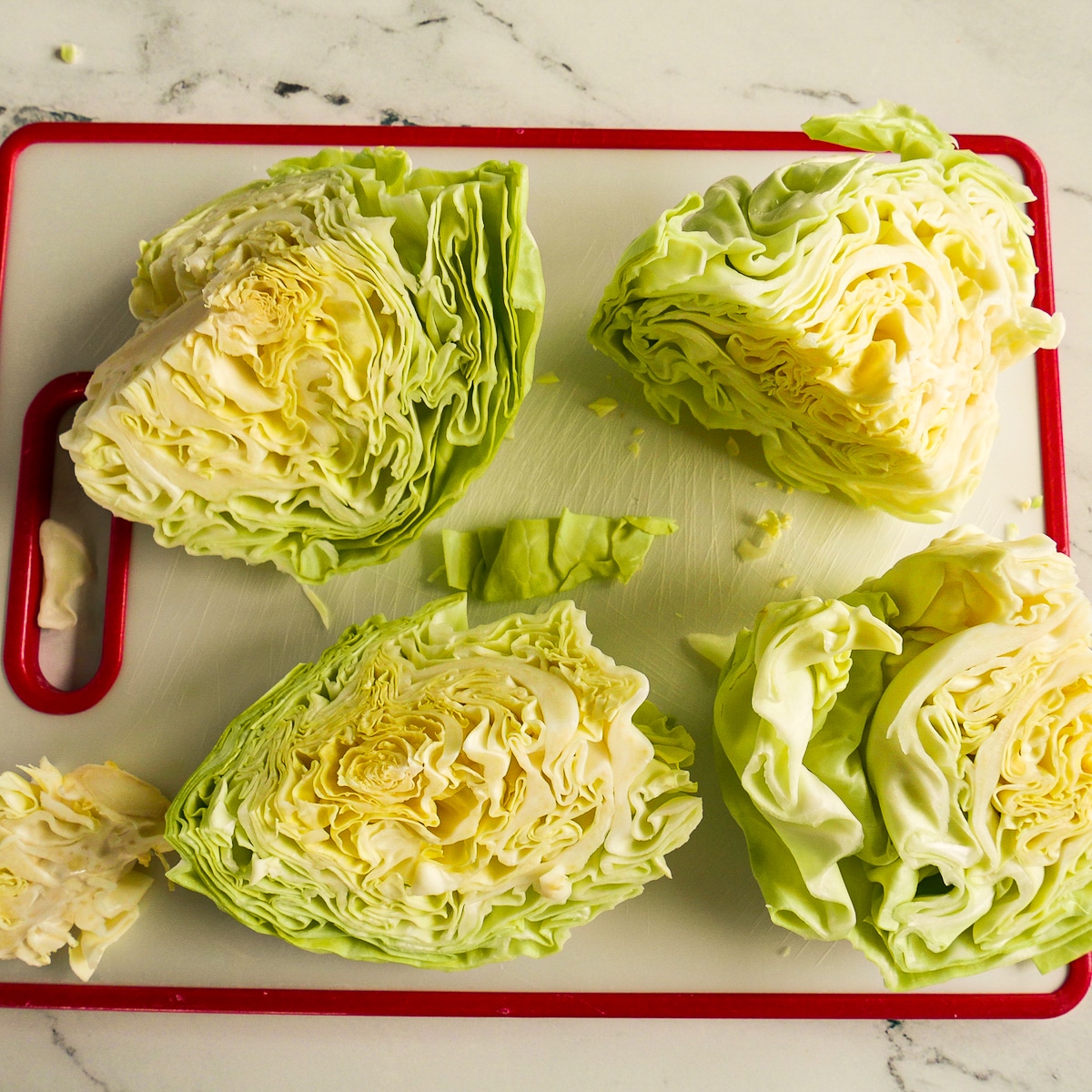 Four sliced cabbage wedges resting on a cutting board.