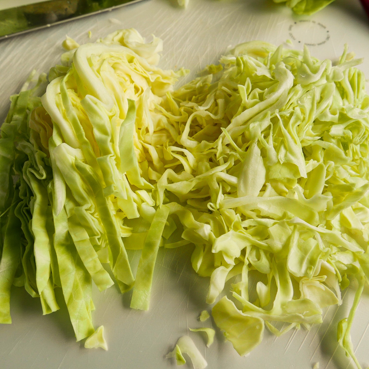 sliced-cabbage.jpg Two piles of sliced green cabbage resting on a cutting board.