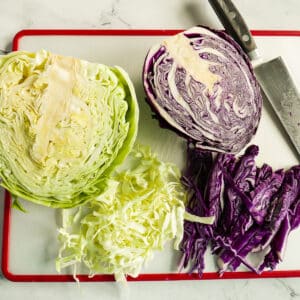 Two halves of green and purple cabbage resting on a cutting board.
