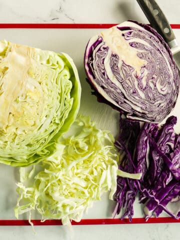 Two halves of green and purple cabbage resting on a cutting board.