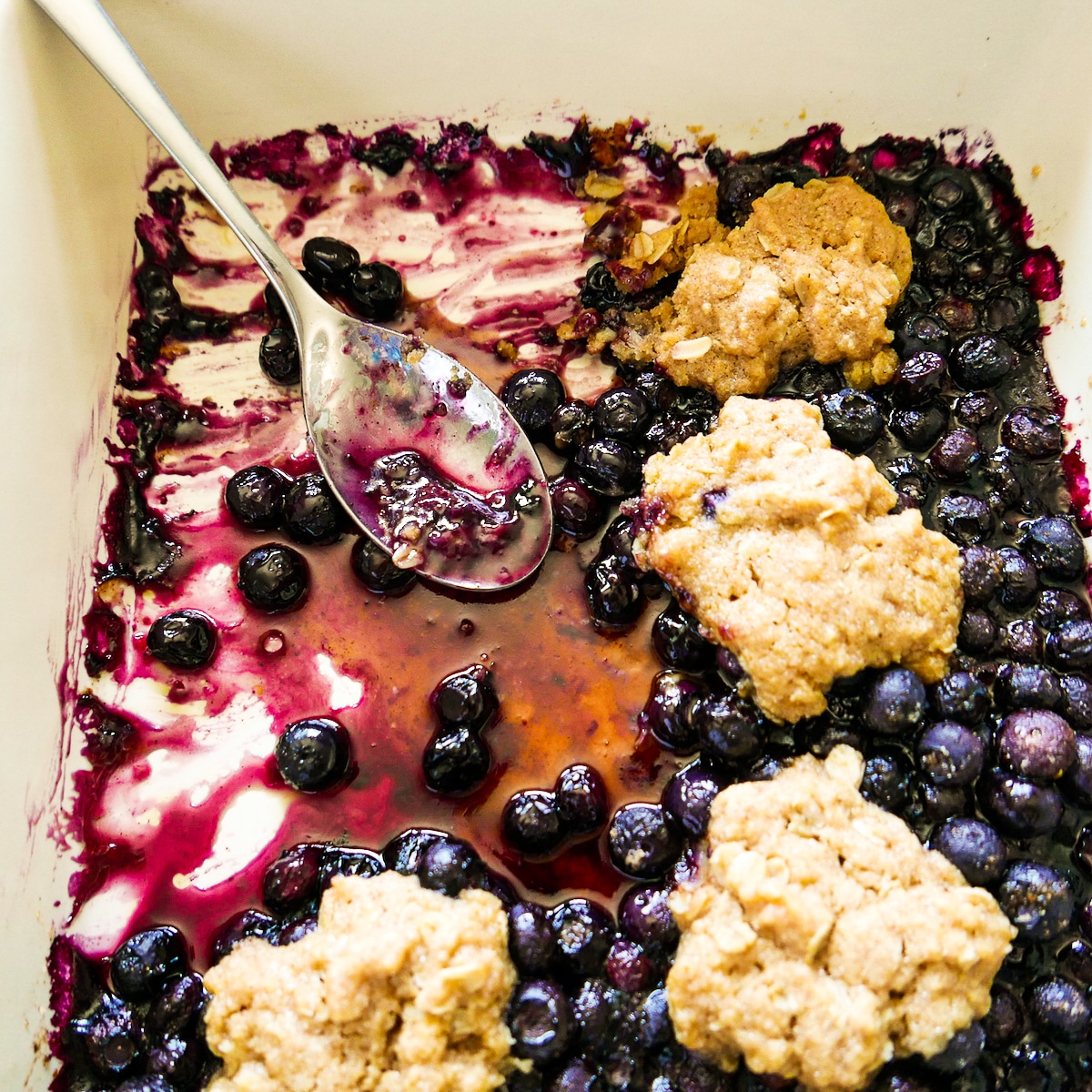 cobbler-in-baking-dish.jpg rustic cobbler in a baking dish with a spoon.