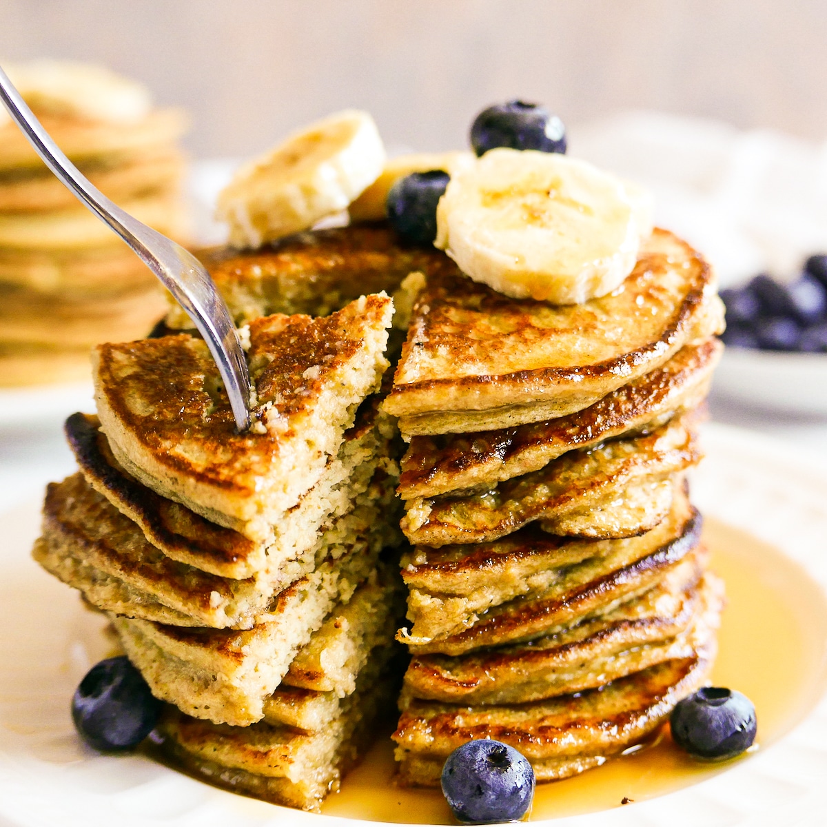 fork-taking-bite-of-pancakes.jpg fork pulling at a large bite of pancakes from plate.