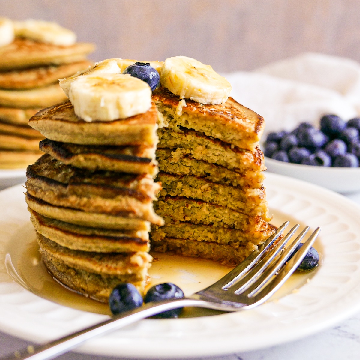 cut-pancakes-with-fork.jpg stack of pancakes that have been cut into with a fork resting on the plate.