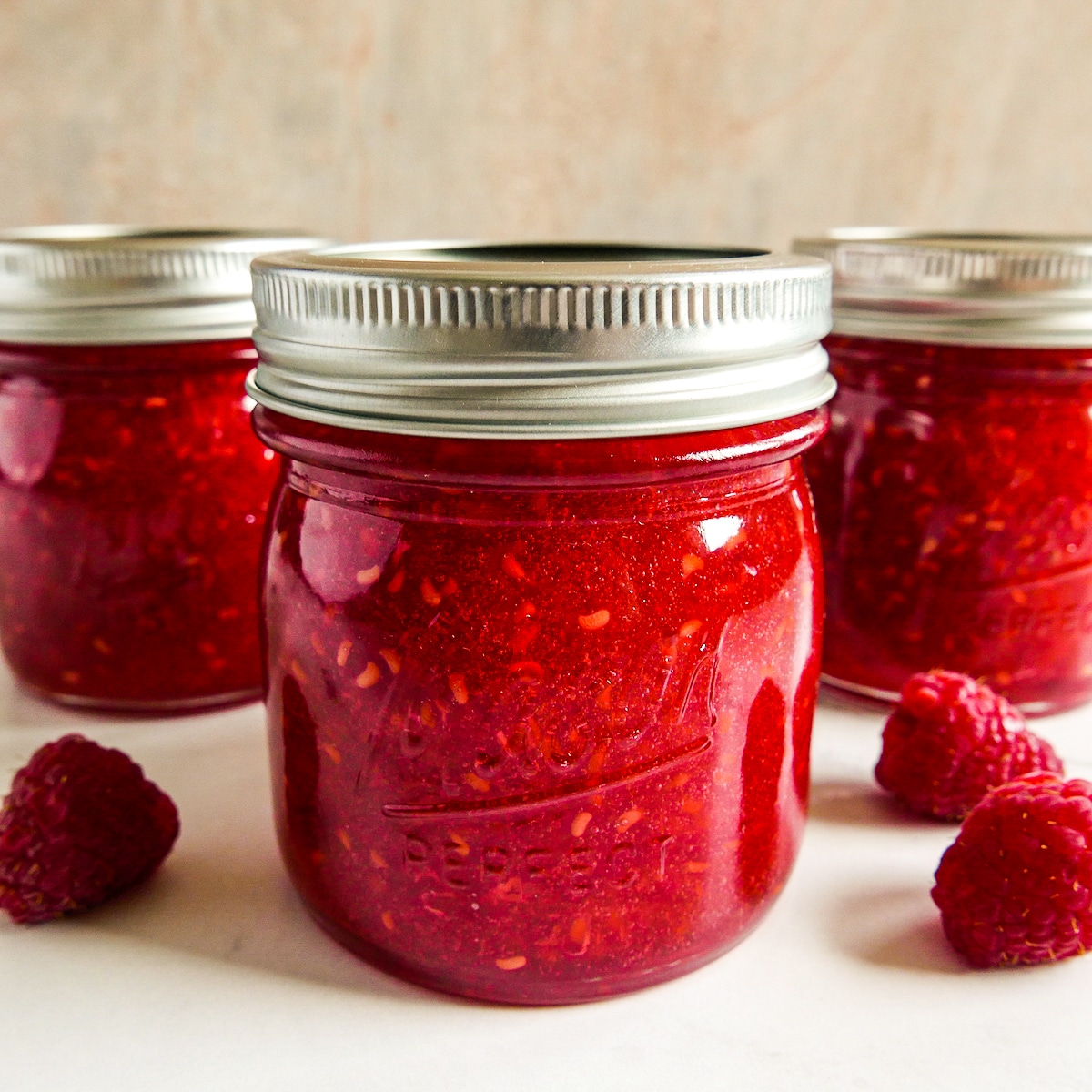 Raspberry jam poured into glass jars with closed lids.