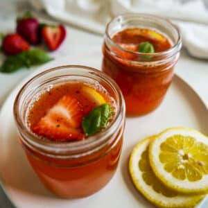 Two glass jars filled with strawberry basil lemonade and garnished with fresh basil.
