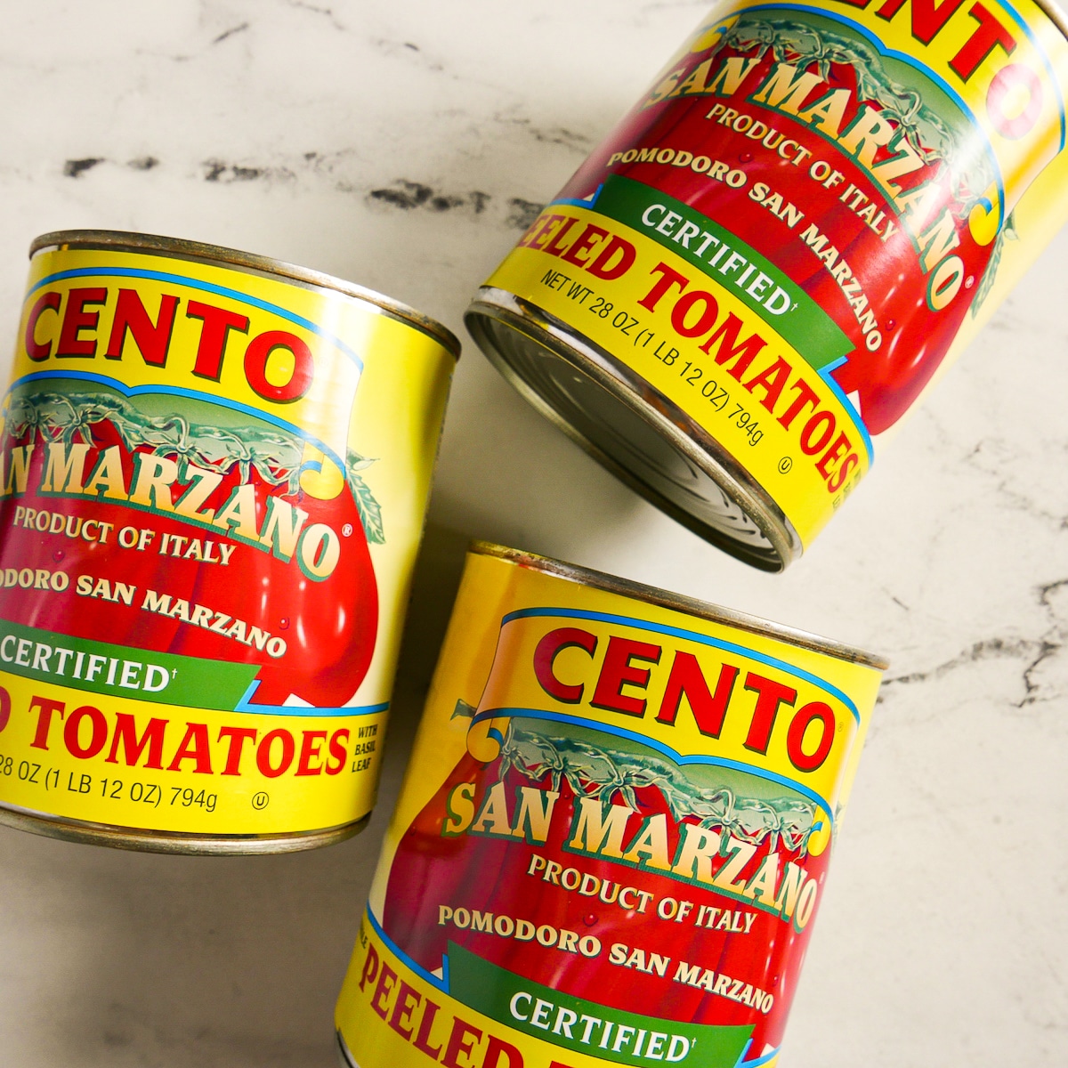 Three cans of San Marzano tomatoes placed on a table.