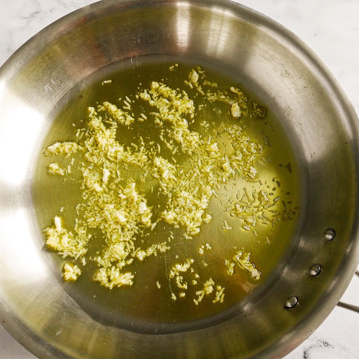 Garlic cooking in a large skillet with olive oil.