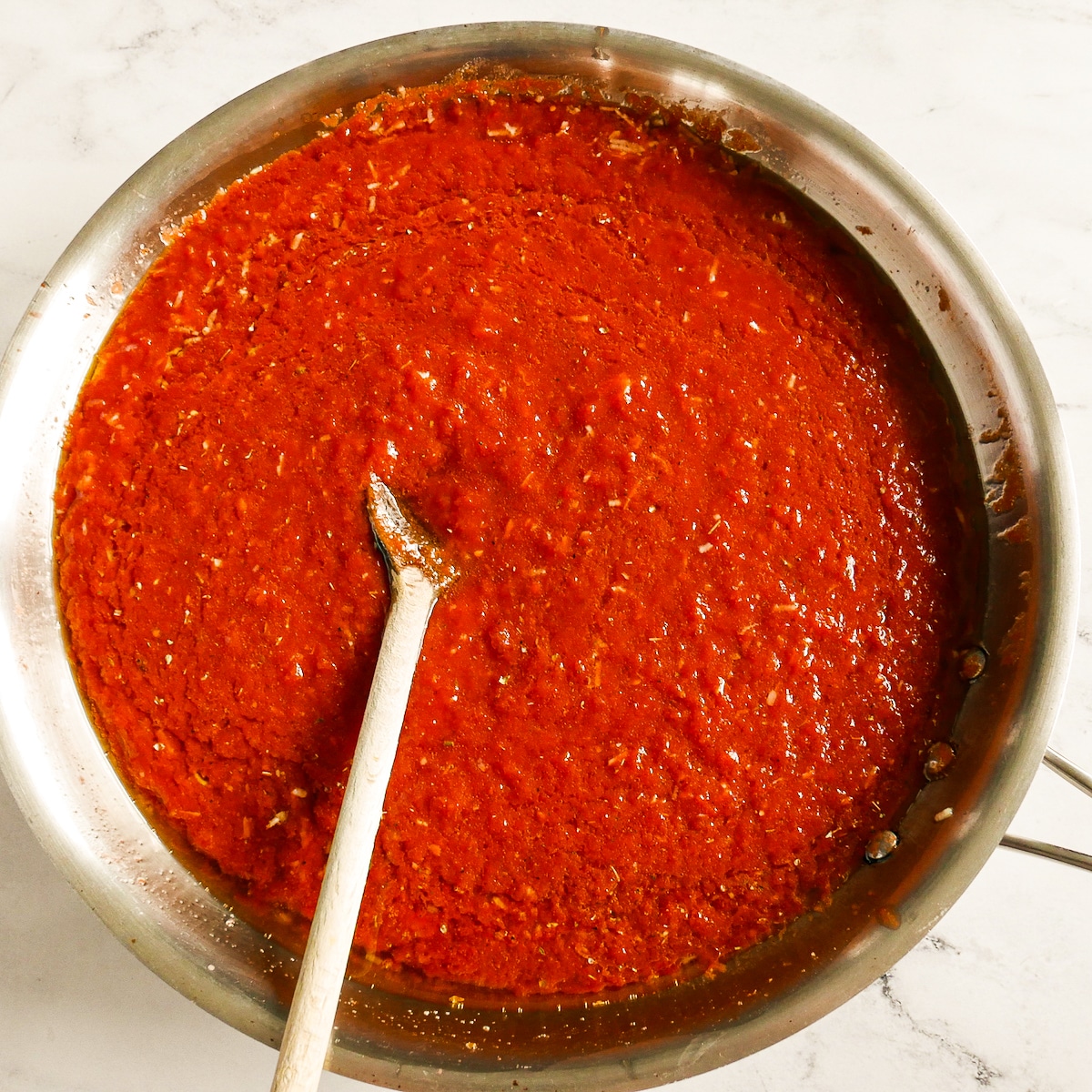 Tomato sauce simmering in a large saucepan.