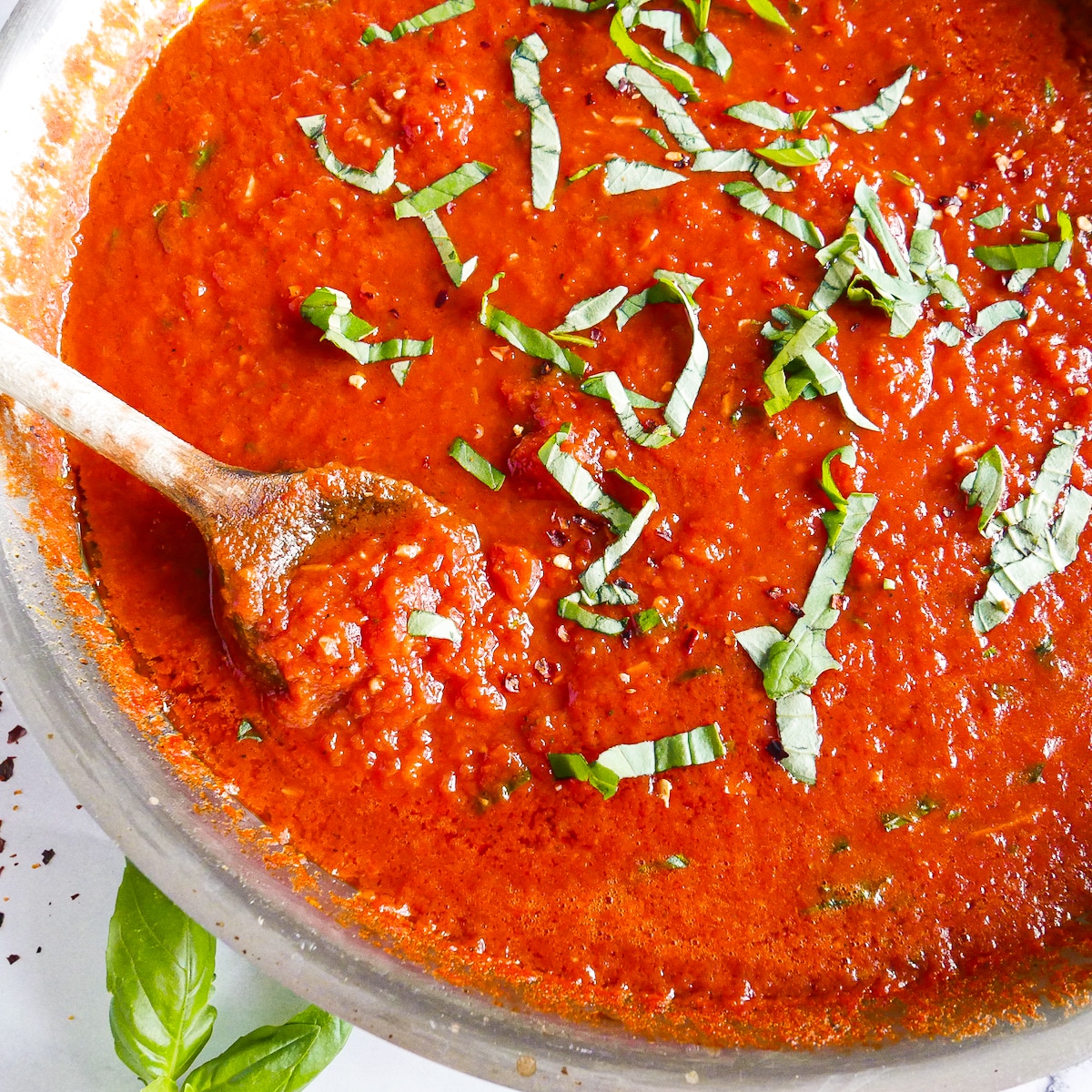 Finished red sauce in a skillet and garnished with fresh basil.