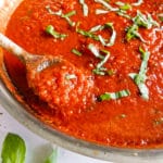 Wooden spoon resting in a pot of Italian tomato sauce.