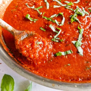 Wooden spoon resting in a pot of Italian tomato sauce.