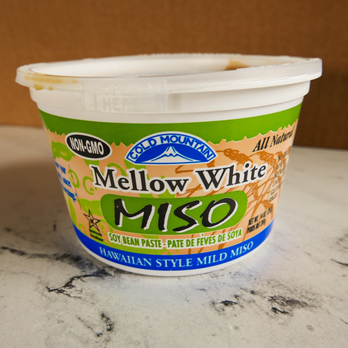 Container of white miso resting on a table.